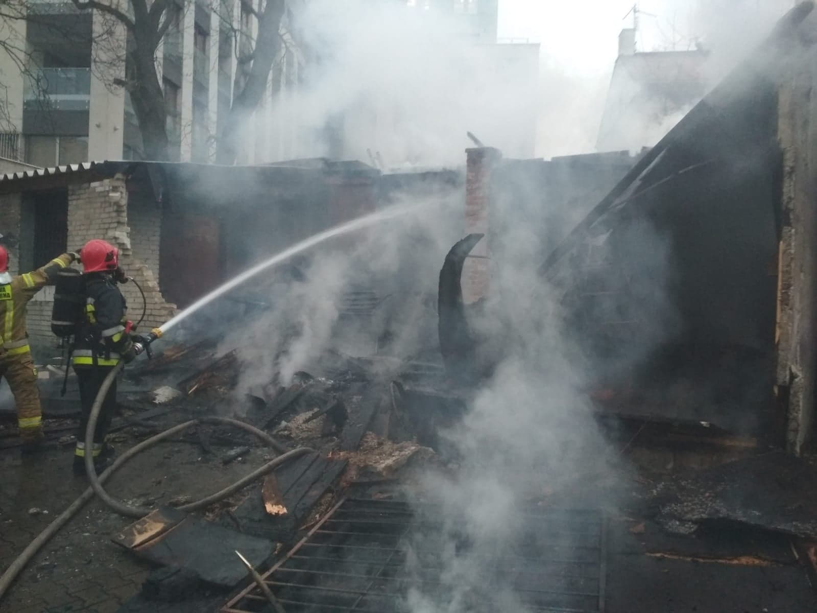 Strażak gaszący strumieniem wody budynek garażu