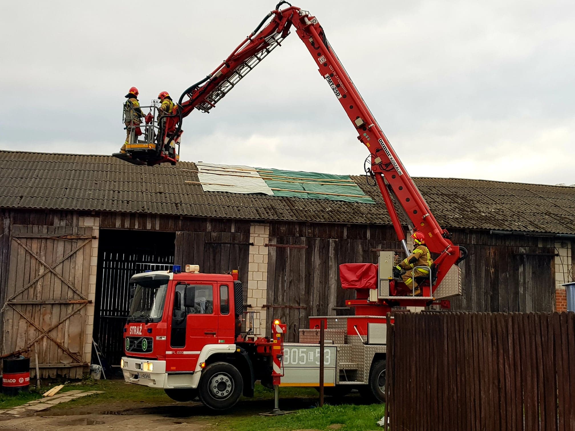 Strażacy na podnośniku zabezpieczający dach stodoły