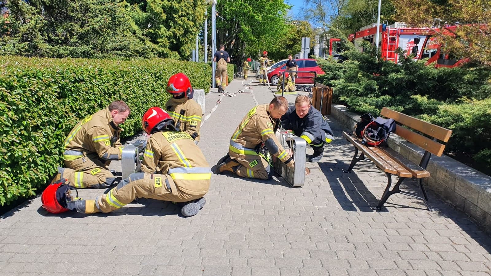 Strażacy ćwiczący rozkładanie lin wężowych na chodniku