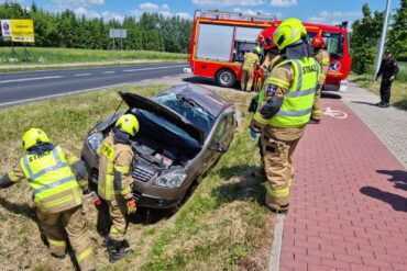 Samochód osobowy, który uległ dachowaniu podczas wypadku oraz strażacy