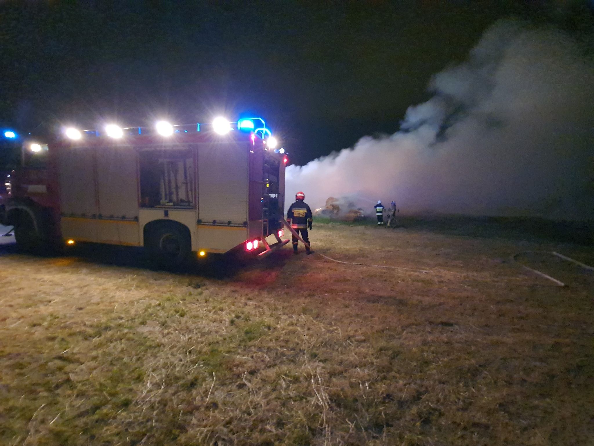 Samochód strażacki oraz dym po gaszeniu słomy