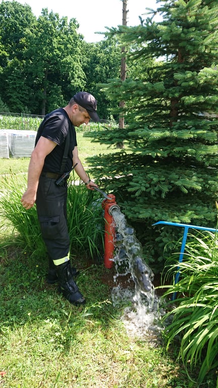 Strażak oraz woda płynąca z hydrantu