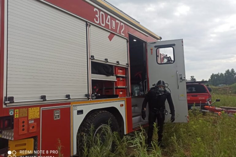 Strażak przy samochodzie strażackim w stroju do nurkowania